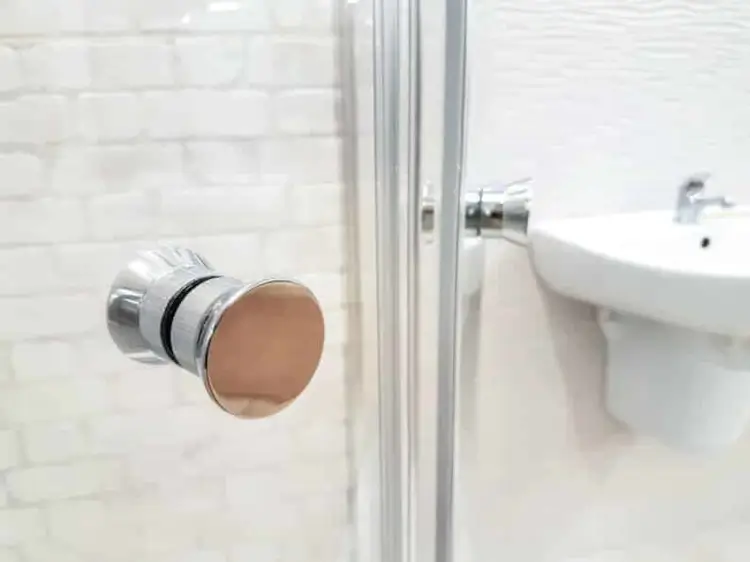 Chrome shower drain cover in a tiled stall, the starting point for how to clean a shower drain