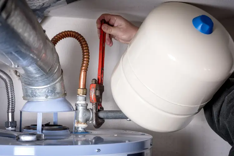 New Orleans plumber making a water heater repair with a pipe wrench